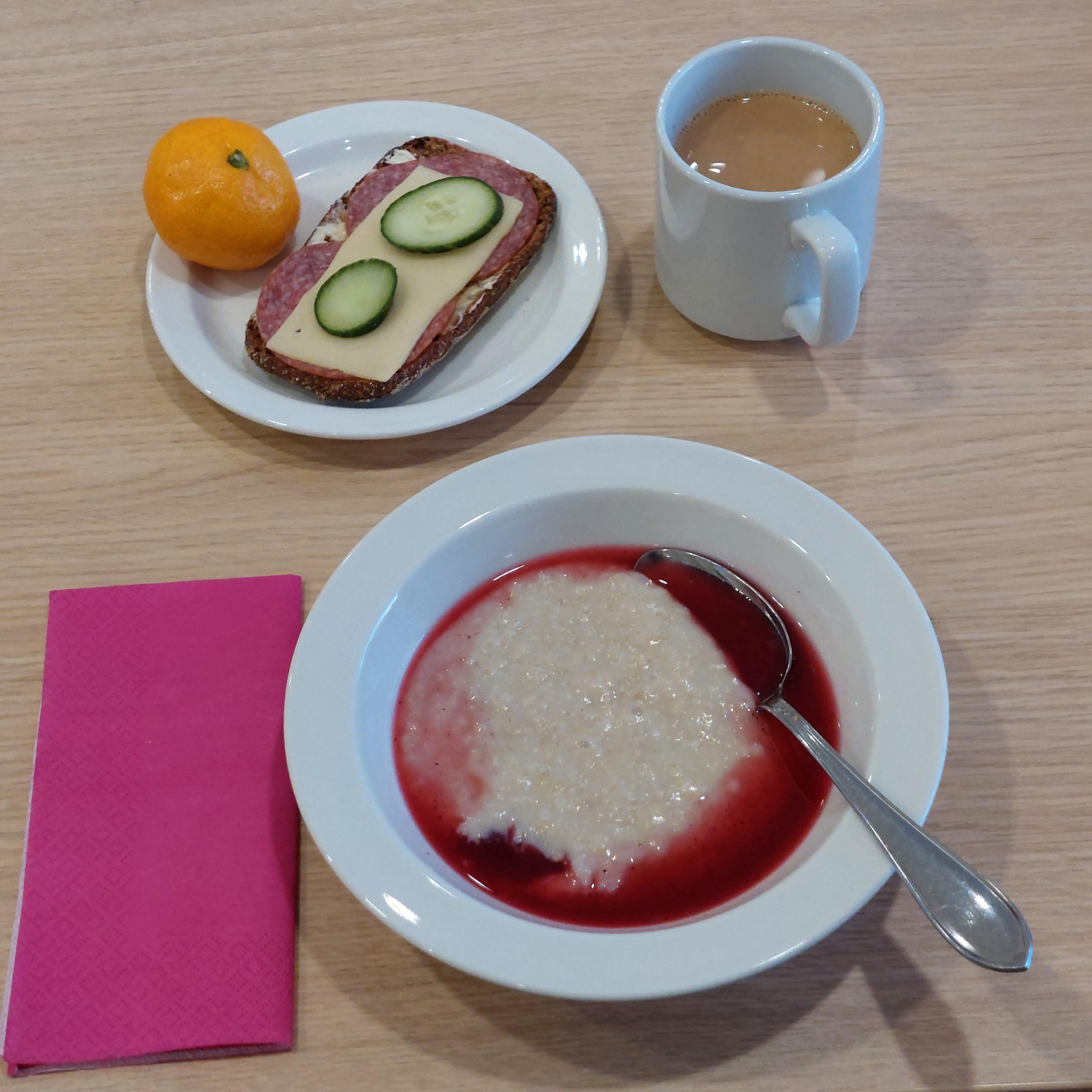 Puurolautanen, kahvia mukissa, voileipä ja mandariini.