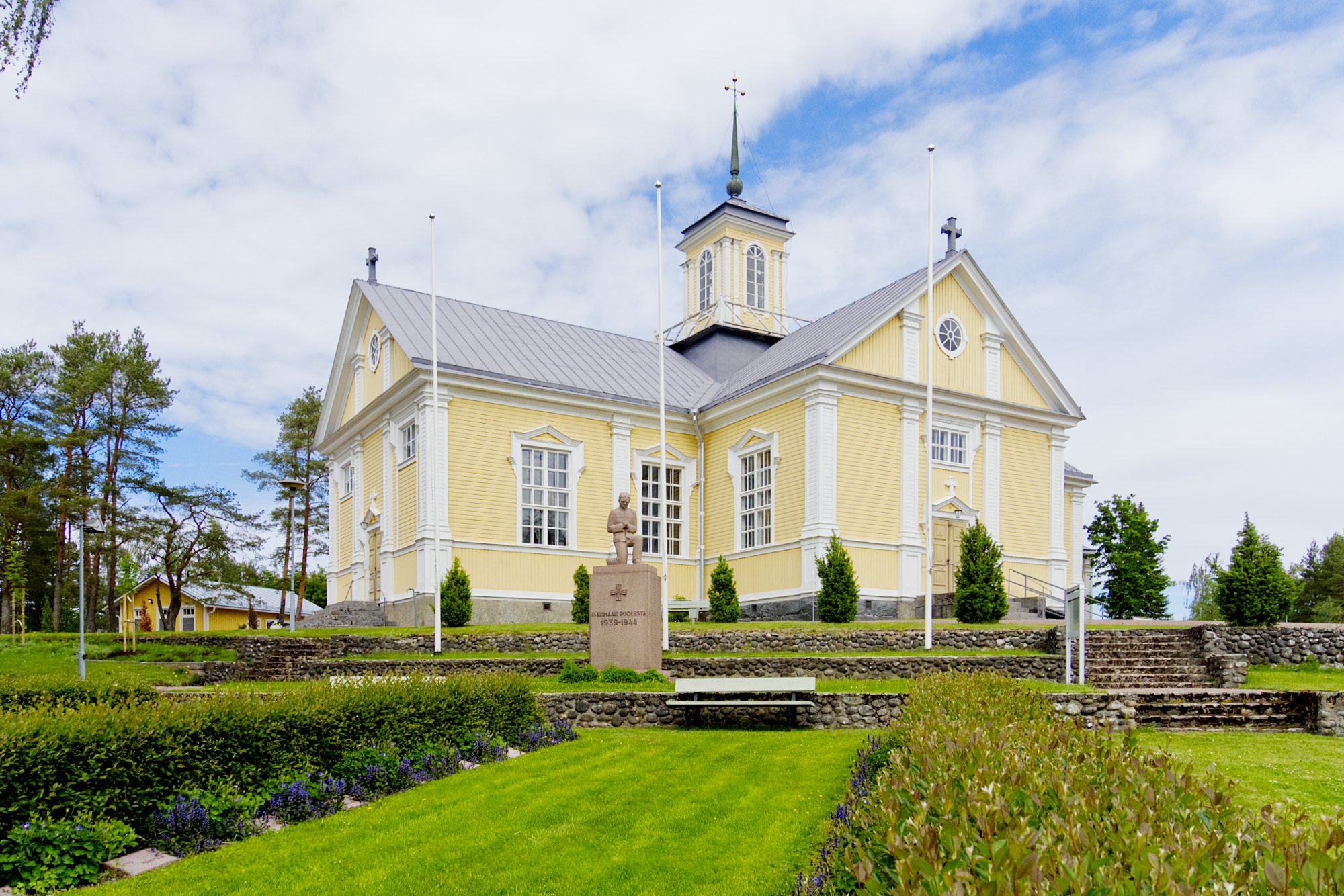 Ahlaisten kirkko kohoaa kesäisen kirkkomaan keskeltä